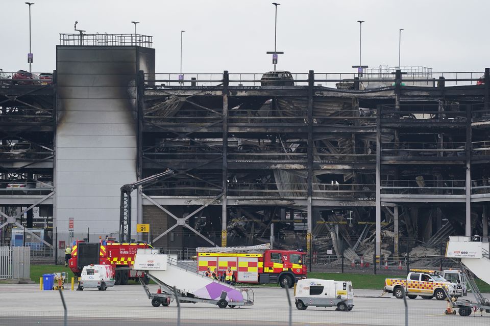 The burned out shells of cars buried amid debris at the multi-storey car park at Luton Airport (Jacob King/PA)