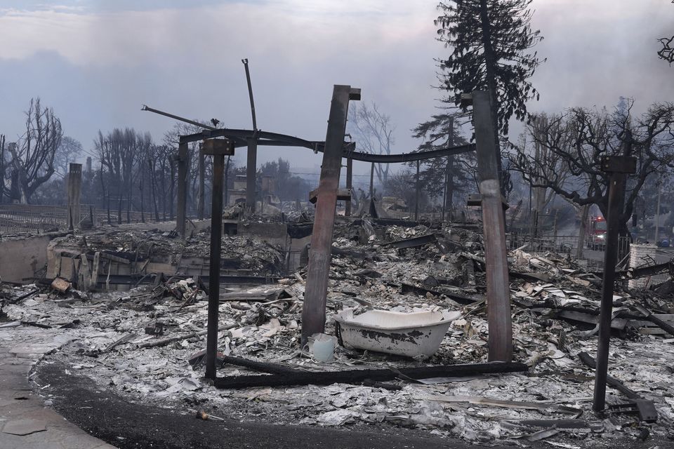 The Palisades Fire ravages a neighbourhood amid high winds (Damian Dovarganes/AP)