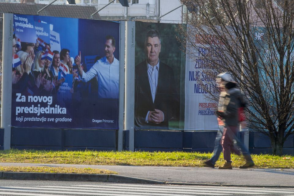 Pedestrians walk past campaign posters of presidential candidates Dragan Primorac and Zoran Milanovic (AP)