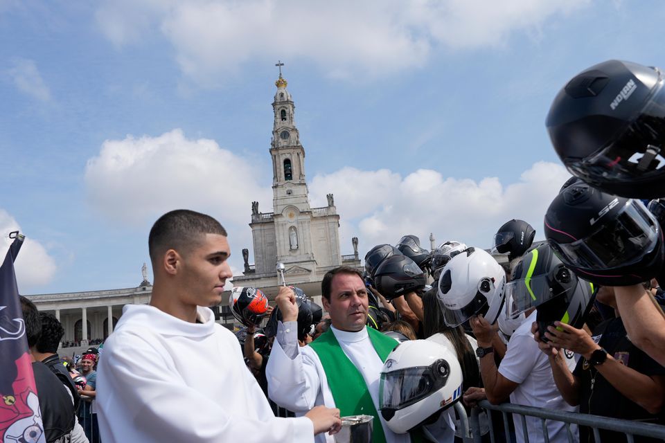 A priest blesses the helmets of faithful in Fatima (Ana Brigida/AP)