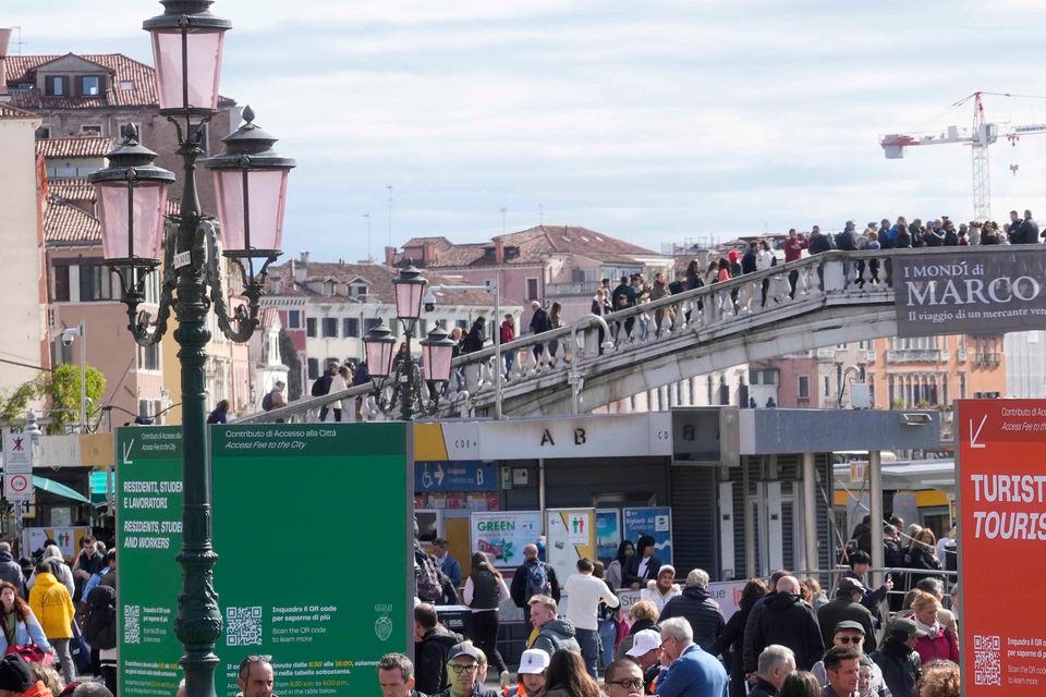 Stewards check tourists’ QR code access outside the main train station in Venice (Luca Bruno/AP)