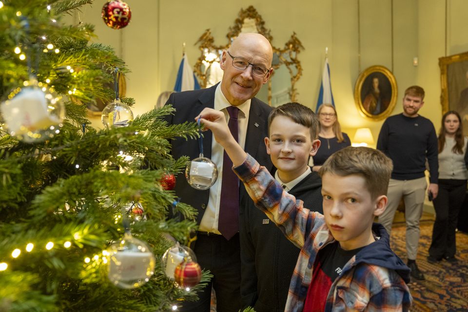 First Minister John Swinney with Kayden Cooper (left), 10, and Jacob Millar, 10, as they hang Christmas baubles (Jane Barlow/PA)