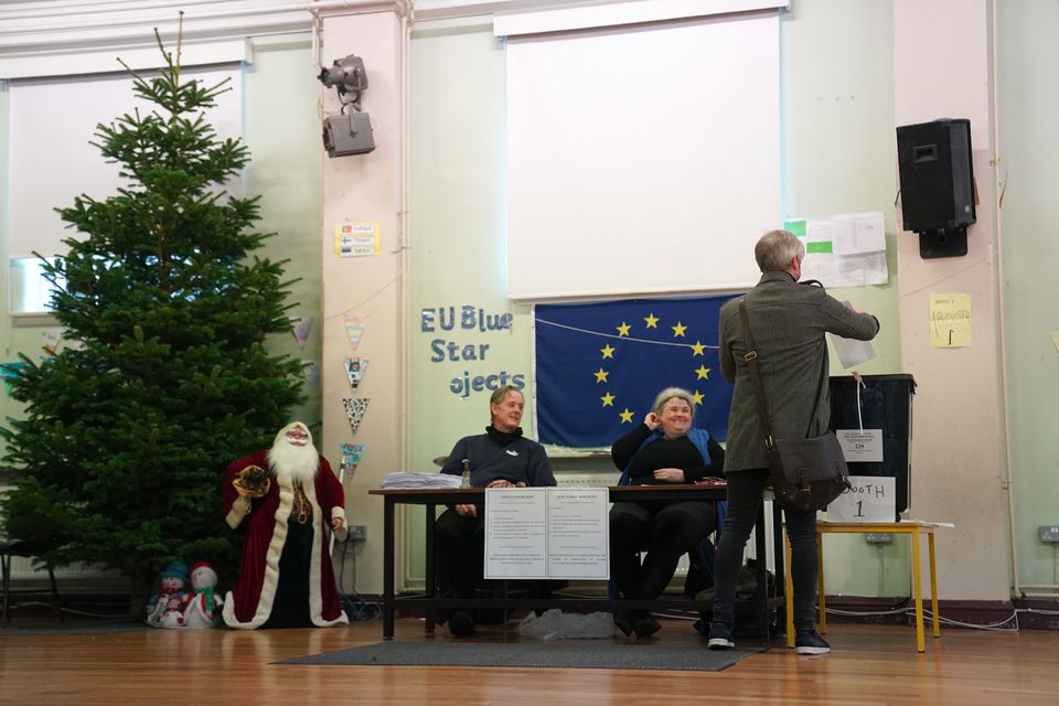 A man drops his vote into a ballot box St Maries of the Isle National School in Cork, watched closely by voting overseers and Father Christmas (Jacob King/PA)