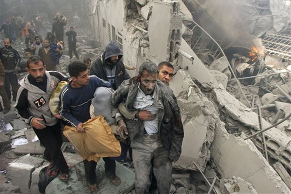 An injured Palestinian prisoner is helped as he and others flee through the rubble of the central security headquarters and prison, known as the Saraya, after it was hit in an Israeli missile strike in in Gaza City, Sunday, Dec. 28, 2008. More than 270 Palestinians have been killed and more than 600 people wounded since Israel's campaign to quash rocket barrages from Gaza began midday Saturday.(AP Photo/Adel Hana)