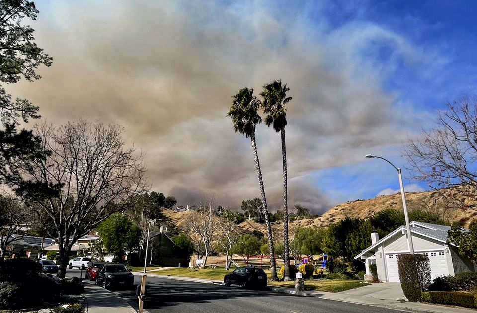 A large plume of smoke rises from Castaic Lake seen behind a neighbourhood in Santa Clarita (Marcio Jose Sanchez/AP)