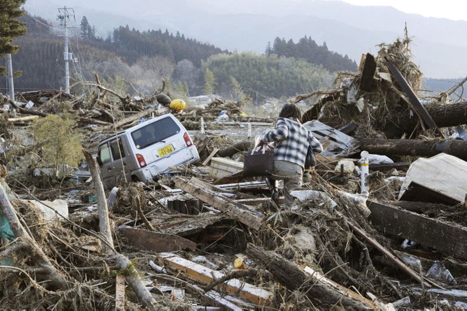A local resident walks through debris in Rikuzentakata, Iwate, northern Japan Saturday morning, March 12, 2011 after Japan's biggest recorded earthquake slammed into its eastern coast Friday