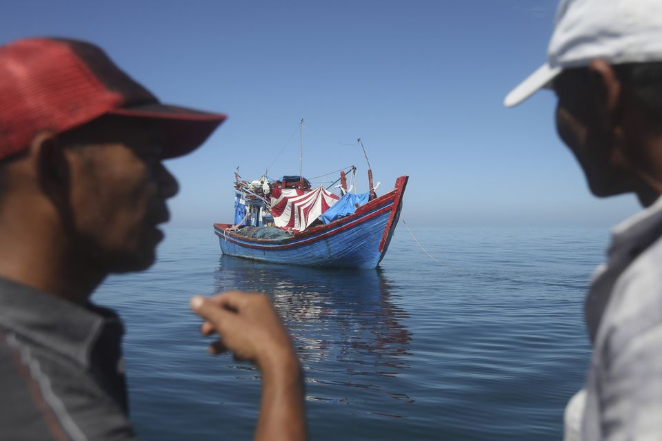 Acehnese men inspect a boat carrying Rohingya refugees anchored in the waters off the coast of Aceh, Indonesia’s northernmost province (Binsar Bakkara/AP)