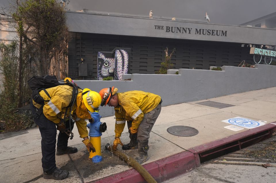 Firefighters work a hydrant in front of the burning Bunny Museum (Chris Pizzello/AP)