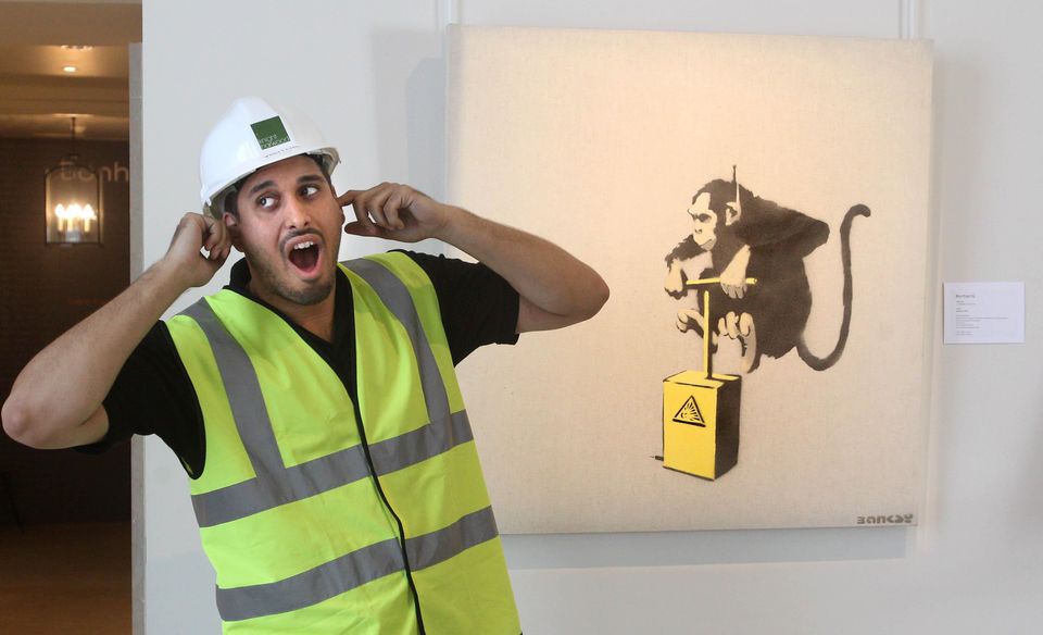 A workman jokes next to Banksy’s Monkey Detonator work (Lewis Whyld/PA)