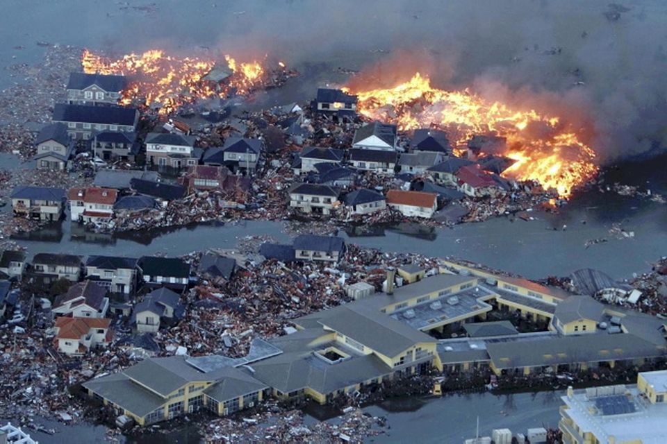 Houses are in flames while the Natori river is flooded over the surrounding area by tsunami tidal waves in Natori city, Miyagi Prefecture, northern Japan, March 11, 2011, after strong earthquakes hit the area