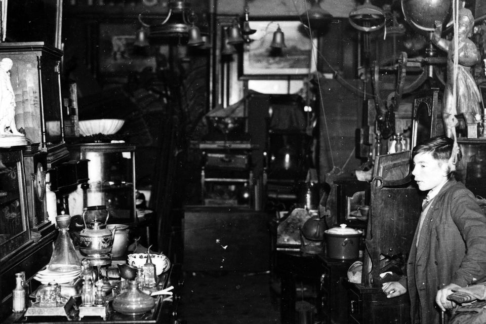 Smithfield market, Belfast.Young boy in a shop selling household furniture lamps and bric a brac. 26/11/1941