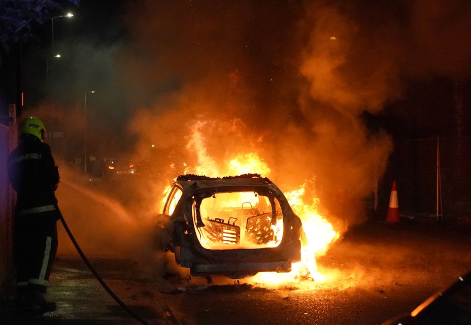 Firefighters tend to a burning police car burns as officers are deployed on the streets of Hartlepool following a violent protest (Owen Humphreys/PA)