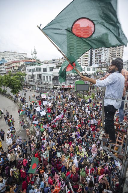 An activist waves a Bangladesh flag during a protest march (Rajib Dhar/AP)