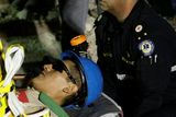 thumbnail: Carlos Mamani, 23, is stretchered off as he becomes the fourth miner to exit the rescue capsule, on October 13, 2010 at the San Jose mine
