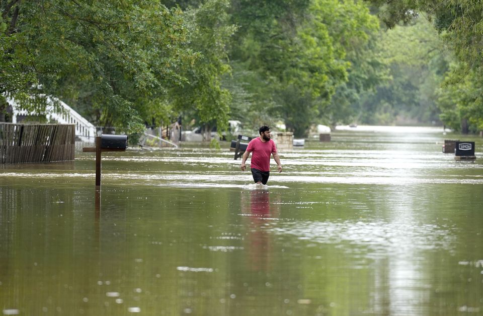 A man walks through floodwaters in Woodloch, Texas (Karen Warren/Houston Chronicle via AP)