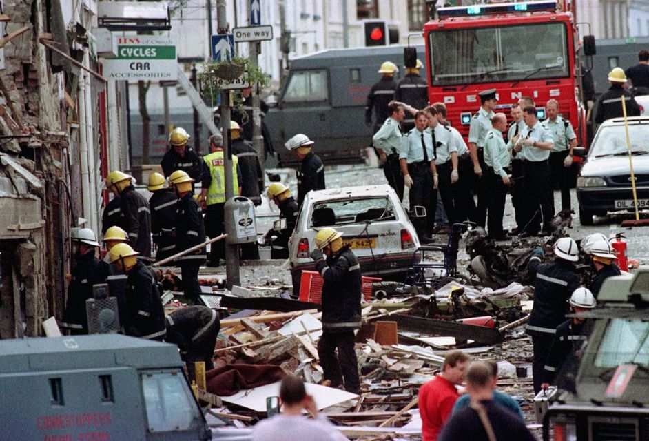 Police officers and firefighters inspecting the damage caused by a bomb explosion in Market Street, Omagh (PA)