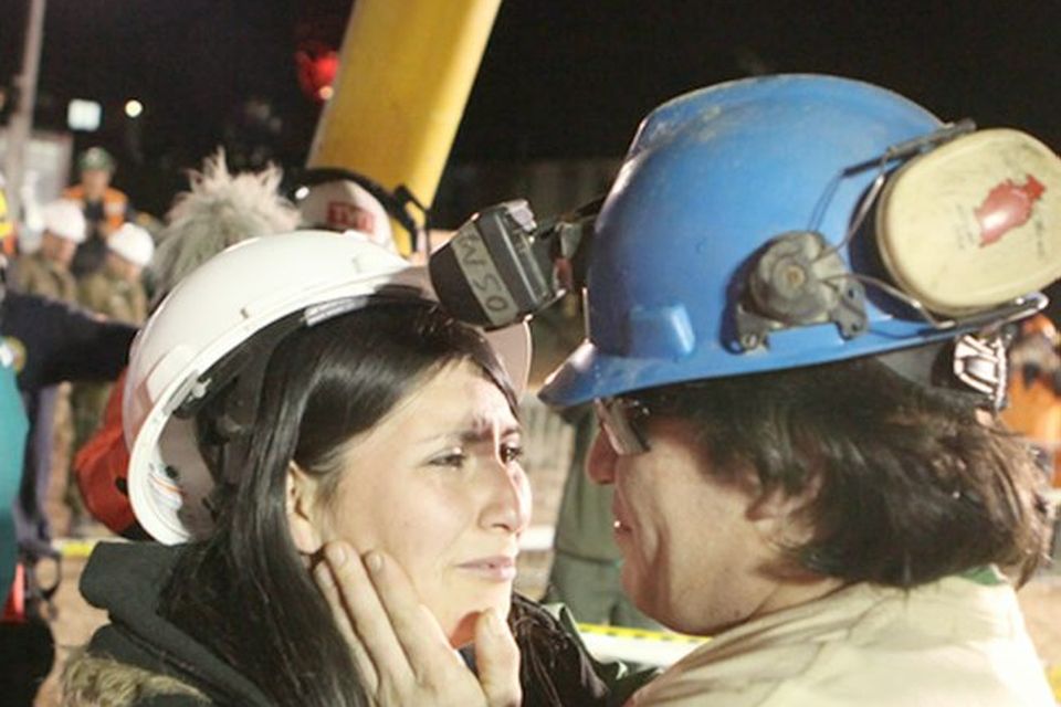 Osman Araya, 29,is hugged by a relative as he becomes the sixth miner to exit the rescue capsule, on October 13, 2010 at the San Jose mine