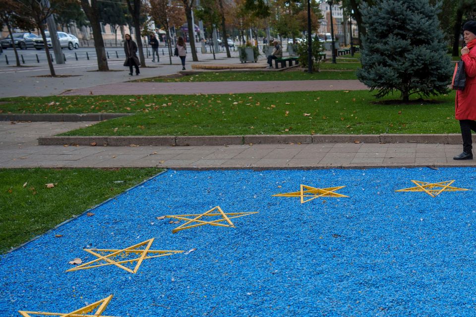 A woman walks by a depiction of the European Union flag near a park in central Chisinau Moldova (AP/Vadim Ghirda)