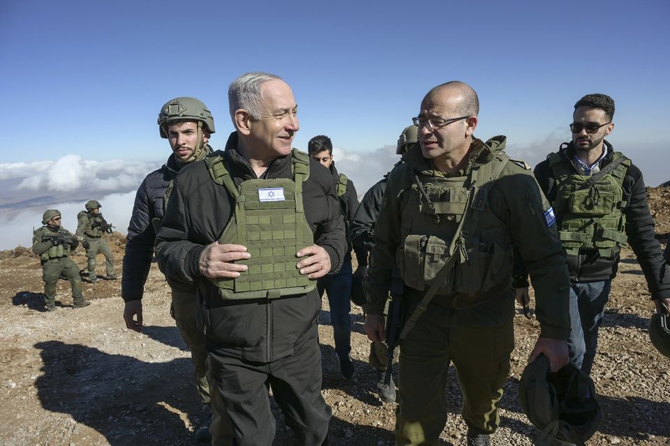 Israel’s Prime Minister Benjamin Netanyahu, left, visits Israeli forces in a buffer zone inside Syria (Israel Government Press Office/AP)