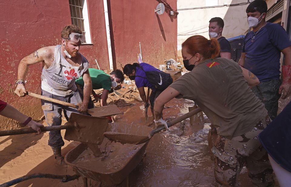 People shovel up mud after floods in Catarroja on the outskirts of Valencia, Spain (Alberto Saiz/AP)