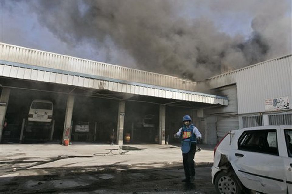 A Unitet Nations worker is seen as smoke billows from Israeli bombardment at the United Nations headquarters in Gaza City, Thursday, Jan. 15, 2009. Witnesses and U.N. officials said that Israeli shells struck the United Nations headquarters in Gaza City.The U.N. chief Ban Ki-moon has expressed "strong protest and outrage" to Israel over the shelling of the compound. (AP Photo/Hatem Moussa)