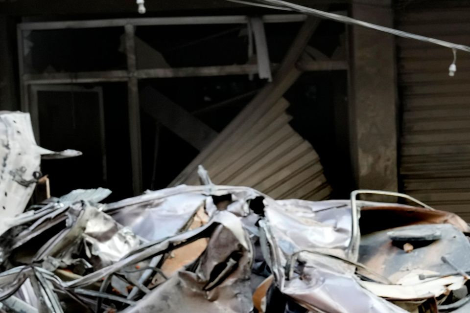 A woman passes in front of destroyed cars at the site of Thursday’s Israeli airstrike in Beirut (AP Photo/Hussein Malla)