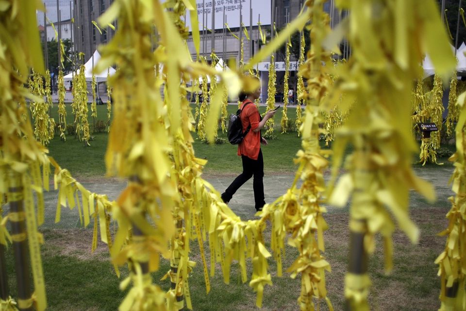 A woman walks near yellow ribbons with messages for missing passengers and victims aboard the sunken South Korean ferry Sewol (AP)
