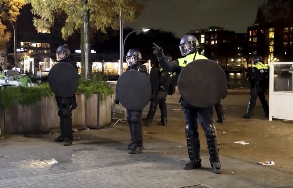 Police officers in riot gear patrol the streets of Amsterdam amid tensions in the city following violence last week (AP)