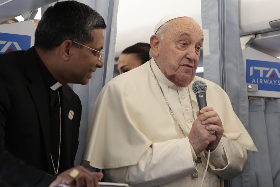 Pope Francis greets the journalists aboard his flight bound for Corsica (Remo Casilli/AP)