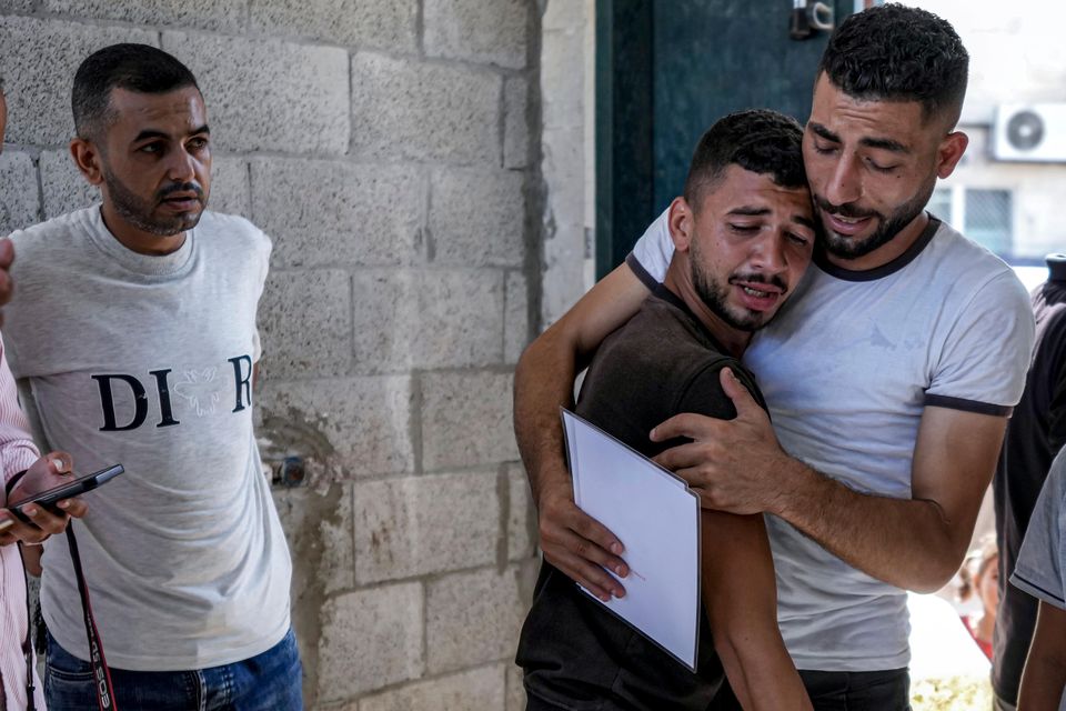 Palestinians mourn their four-day-old twin relatives, killed in the Israeli bombardment of the Gaza Strip, as he holds their birth certificates, at a hospital morgue (Abdel Kareem Hana/AP)