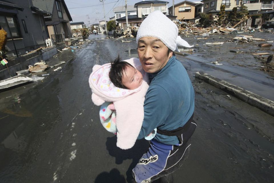 Upon hearing another tsunami warning, a father tries to flee for safety with his just reunited four-month-old baby girl who was spotted by Japan's Self-Defense Force member in the rubble of tsunami-torn Ishinomaki Monday, March 14, 2011, three days after a powerful earthquake-triggered tsunami hit northeast Japan.