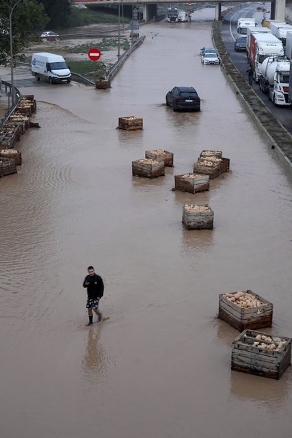 A man walks on a flooded motorway in Valencia (Alberto Saiz/AP)