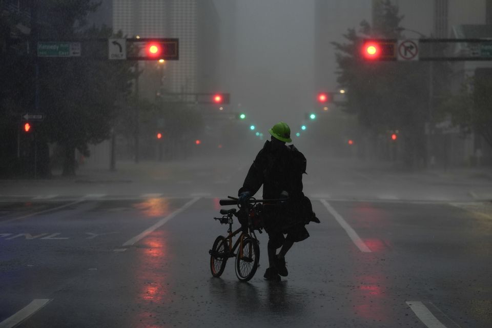 Ron Rook, who said he was looking for people in need of help or debris to clear, walks through windy and rainy conditions on a deserted street in downtown Tampa (Rebecca Blackwell/AP)