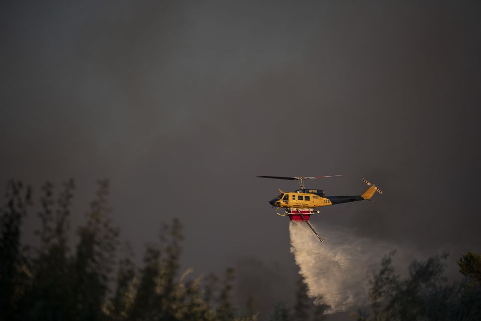 A helicopter drops water near Varnava village during a wildfire (Michael Varaklas/AP)