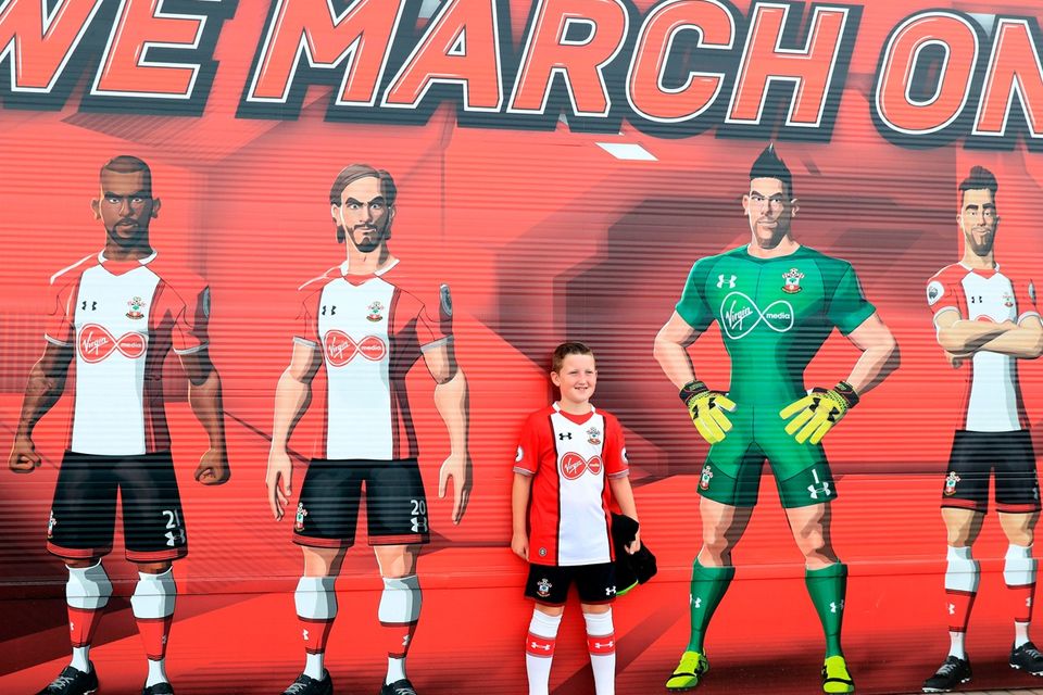 The beautiful game - football fans from around the world -  A young Southampton fan poses for a picture next to a player mural before the Premier League match at St Mary's, Southampton.