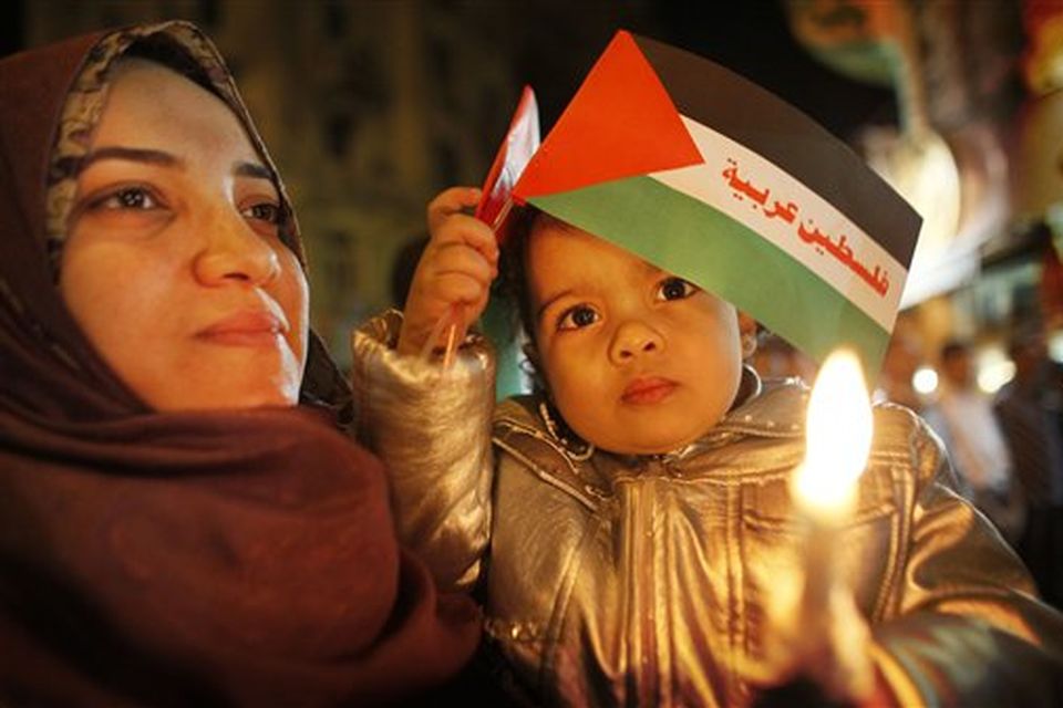 Mariam Khalid, 2, holds a Palestinian flag with writing in Arabic reading "An Arab Palestine" as she is held by her mother Nagwa, at a candlelit vigil in a show of mourning and support for those who have died in Gaza, at Talaat Harb square in downtown Cairo, Egypt, Monday, Jan. 12, 2009. Israel's offensive in Gaza has sparked widespread anger across the Middle East, and Egypt, which shares a border with Gaza, has come under criticism for only allowing limited openings of its border - a move seen by many as abetting Israel's siege of Gaza's 1.4 million residents. (AP Photo/Ben Curtis)