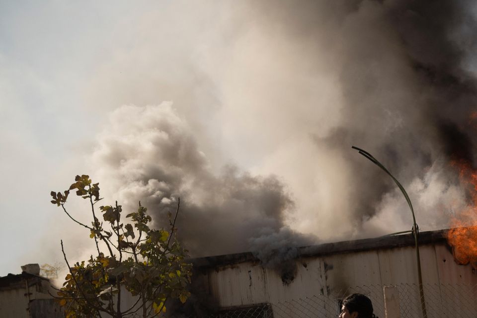 A Syrian fighter carries his weapon past a burning house during a raid to stop looters on the outskirts of Damascus (Leo Correa/AP)