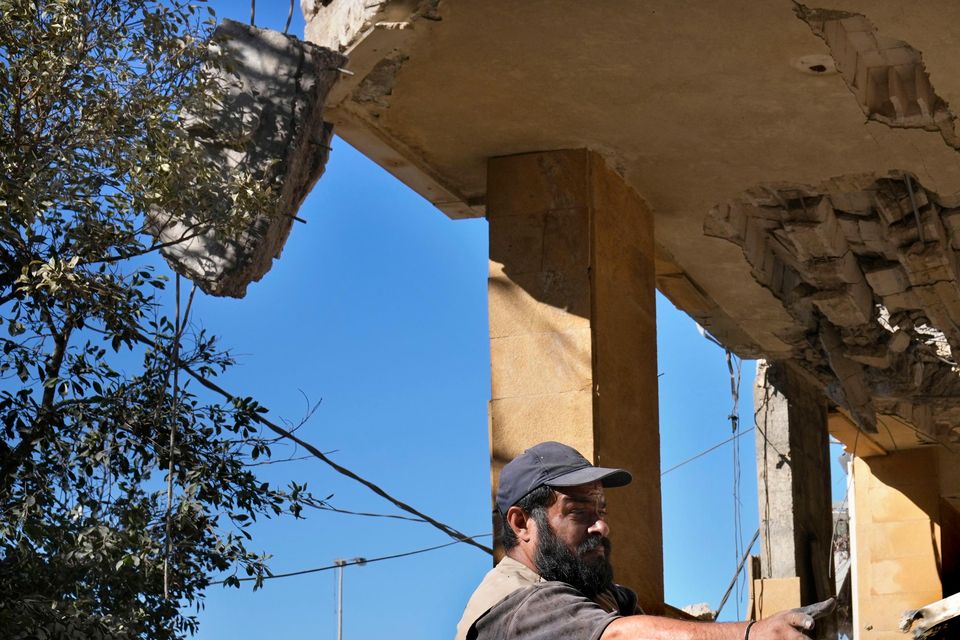 A worker removes the debris of a building that housed the office of pan-Arab TV channel Al-Mayadeen on Thursday (Hussein Malla/AP)