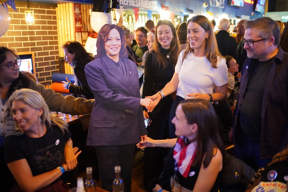 People pose for photos with a cardboard cutout of Kamala Harris at the Democrats Abroad US election watching event in central London (Yui Mok/PA)