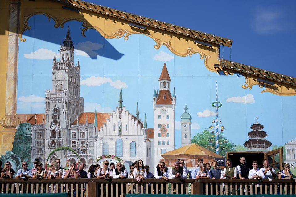 Visitors await the start of the Oktoberfest’ beer festival in front of paintings showing Munich landmarks (Matthias Schrader/AP)