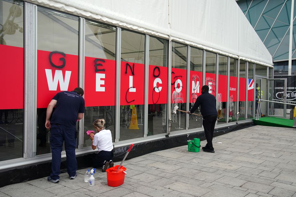 People remove graffiti sprayed by Youth Demand on the security check-in building (Peter Byrne/PA)