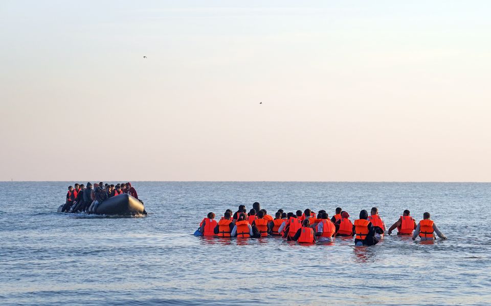 A group of people thought to be migrants wade through the sea to clamber aboard a small boat off the beach in Gravelines, France (Gareth Fuller/PA)