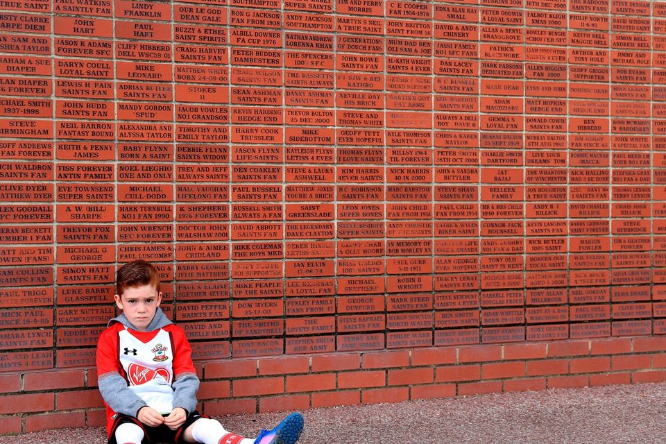 The beautiful game - football fans from around the world -  A young Southampton fan next to a brick memorial wall before the Premier League match at St Mary's, Southampton.