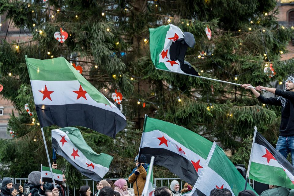 People wave Syrian opposition flags at City Hall Square in Copenhagen, Denmark (Emil Nicolai Helms/Ritzau Scanpix via AP)