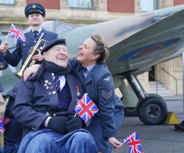 Henry Rice, 98, who served aboard HMS Eastway on VE Day, reacts to receiving a kiss from D-Day Darlings lead singer Katie Ashby (Jonathan Brady/PA)