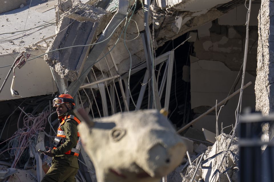 An officer from the home front command military unit examines the damage after a large piece of shrapnel from a Houthi missile hit a school building in Ramat Gan, a suburb of Tel Aviv (Ariel Schalit/AP)