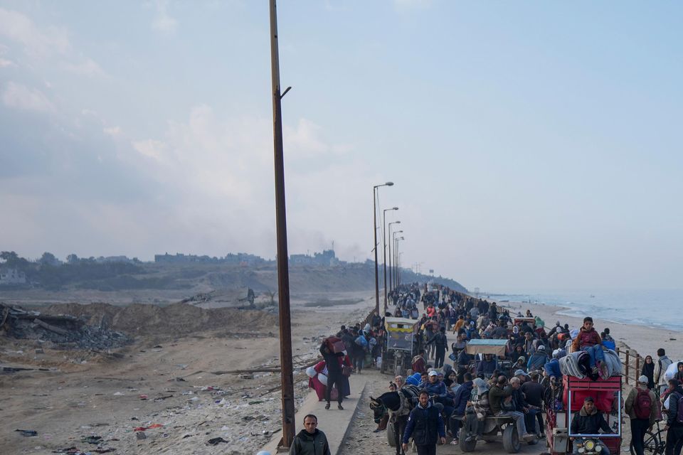 Displaced Palestinians walk on a road in central Gaza to return to their homes following the Israel-Hamas ceasefire deal (Abdel Kareem Hana/AP)