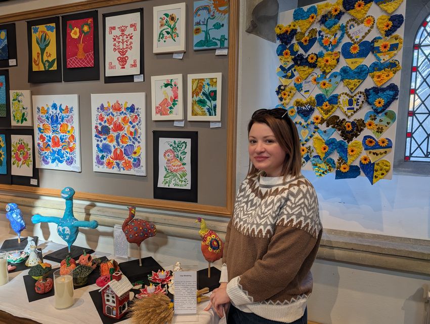 Maryna Melnyk next to some art in the exhibit (Bridge to Unity/PA)