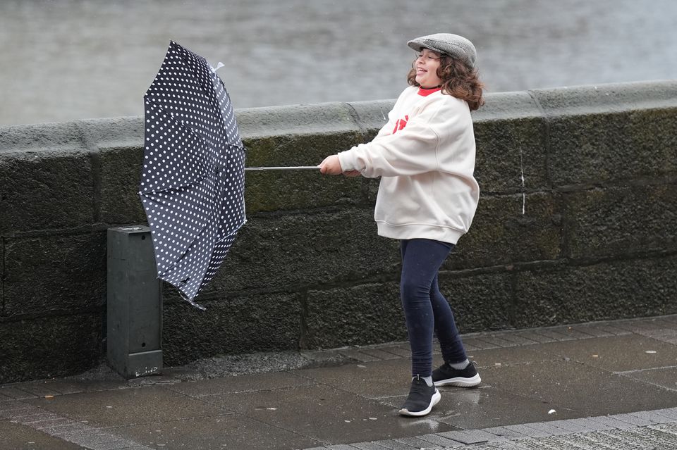 Catarina Haubert, 10, from Brazil, struggles with her umbrella as the wind picks up in Dublin city centre (Niall Carson/PA)