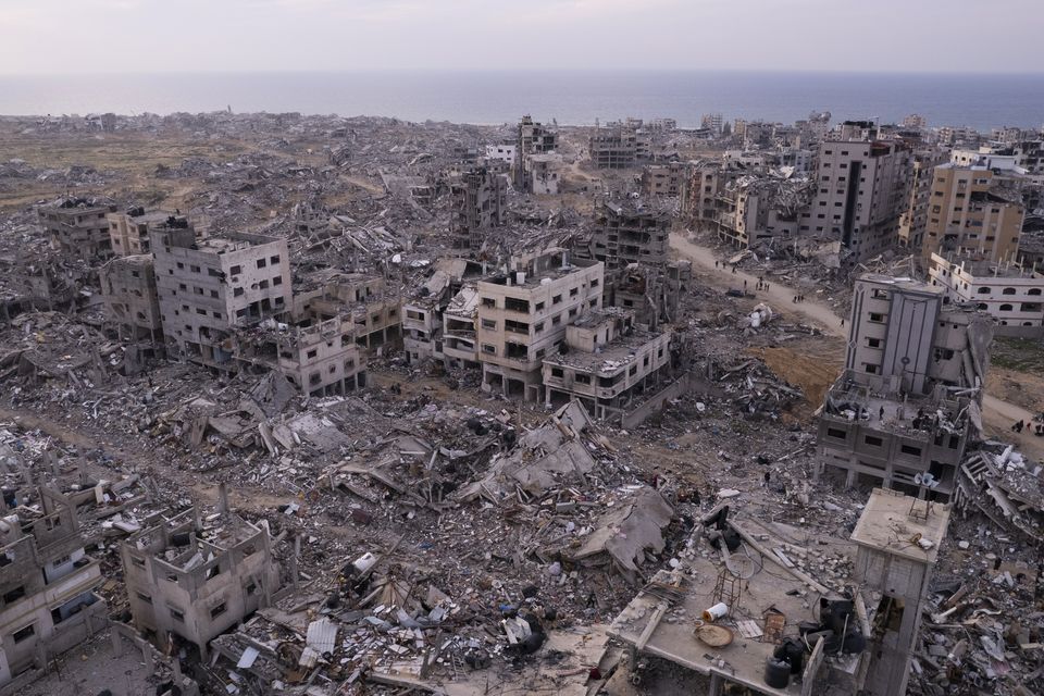 Palestinians walk through buildings that were destroyed by the Israeli air and ground offensive in Tel al-Hawa, Gaza Strip (Mohamamd Abu Samra/AP)